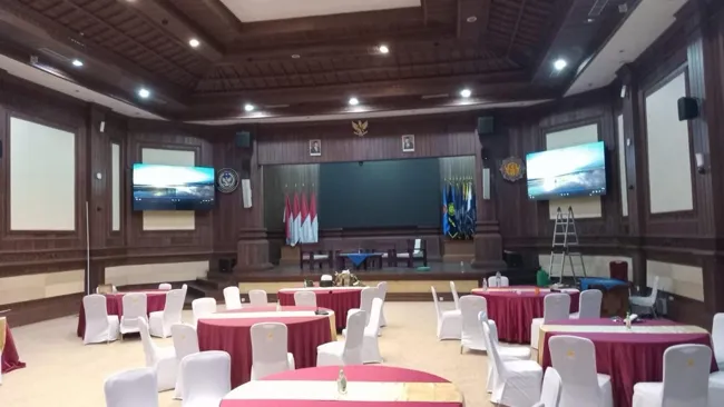 Ruang aula dengan layar presentasi di sisi kiri dan kanan