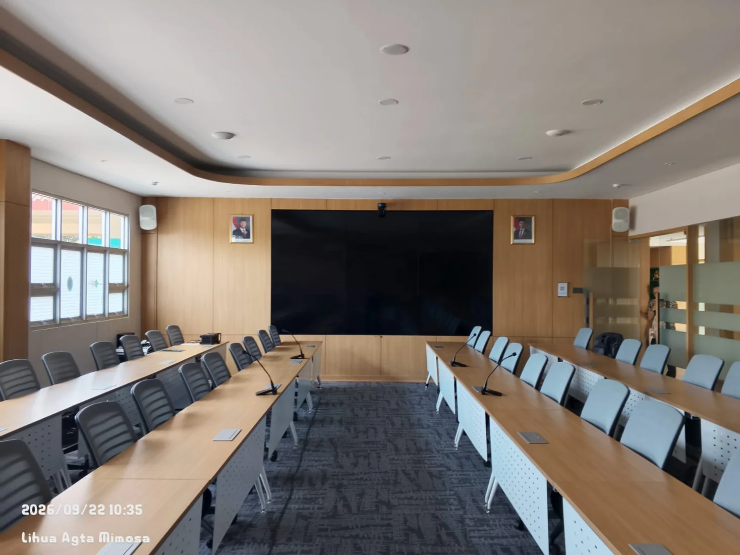 Ruang rapat modern dengan layar besar dan mikrofon konferensi
